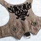 An overhead view of the inner lining of a brown tweed cat harness with a diagonal stripes pattern. The lining is a plain black fabric. A black leash attachment point with a silver D-ring is visible at the bottom.