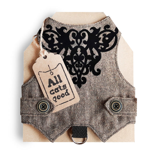 An overhead view of the inner lining of a brown tweed cat harness with a diagonal stripes pattern. The lining is a plain black fabric. A black leash attachment point with a silver D-ring is visible at the bottom.