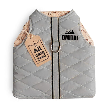 A quilted light grey cat harness with black trim, a reflective stripe, a personalized "DMITRI" text with a mountain icon, and an Allcatsgood tag.